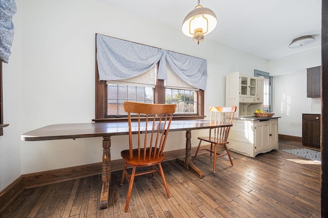 dining space with dark wood finished floors and baseboards