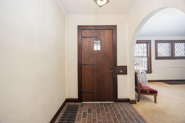 entryway featuring dark carpet, baseboards, ornamental molding, and arched walkways