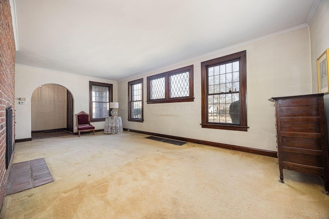 unfurnished room featuring arched walkways, carpet flooring, crown molding, and visible vents