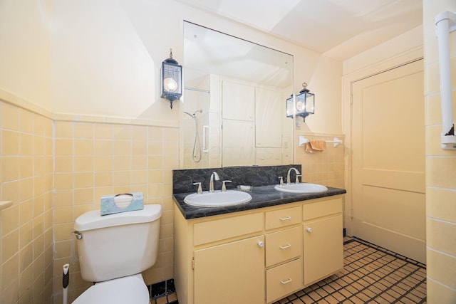 bathroom featuring a sink, tile walls, toilet, and double vanity