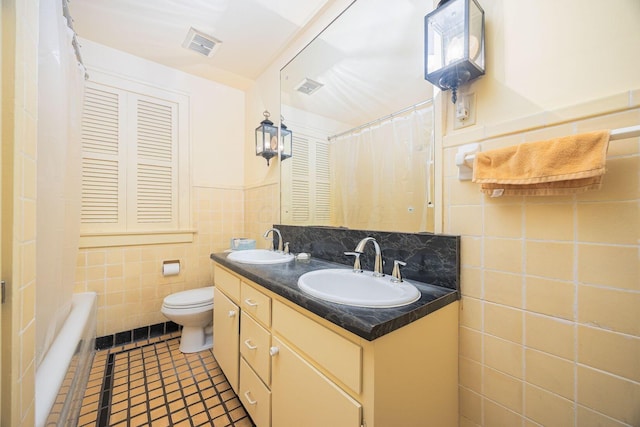 full bath featuring visible vents, a sink, tile walls, and toilet