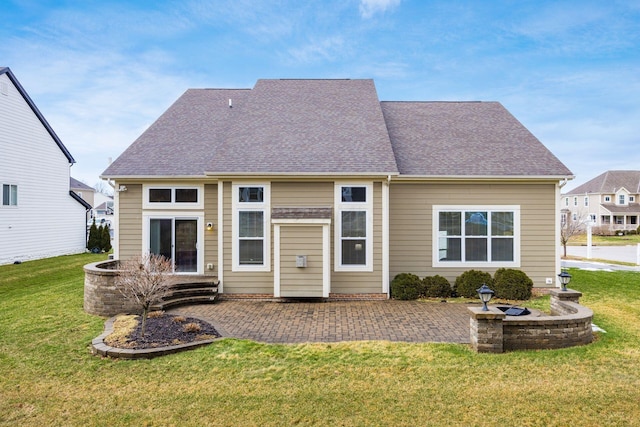 back of house featuring a yard, roof with shingles, and a patio area