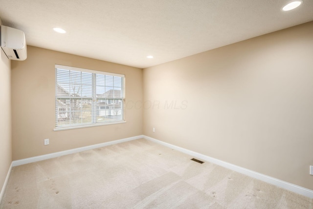 empty room with a wall unit AC, recessed lighting, baseboards, and light colored carpet