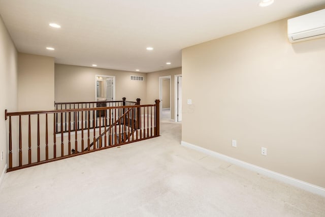 unfurnished room featuring visible vents, baseboards, light colored carpet, a wall mounted air conditioner, and recessed lighting