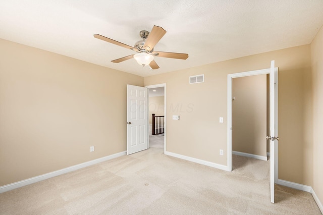 unfurnished bedroom with light carpet, a ceiling fan, visible vents, and baseboards