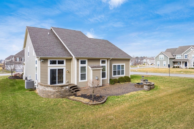 back of house featuring a residential view, a lawn, and central AC