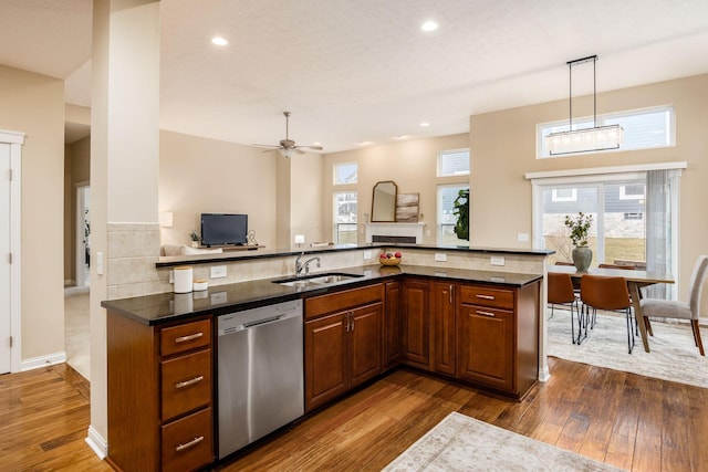 kitchen featuring dark wood-style floors, a sink, hanging light fixtures, brown cabinets, and dishwasher