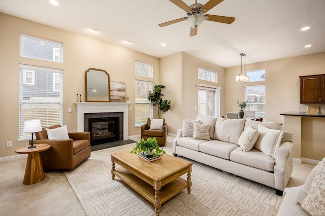 living room with a textured ceiling, a tile fireplace, recessed lighting, light carpet, and baseboards