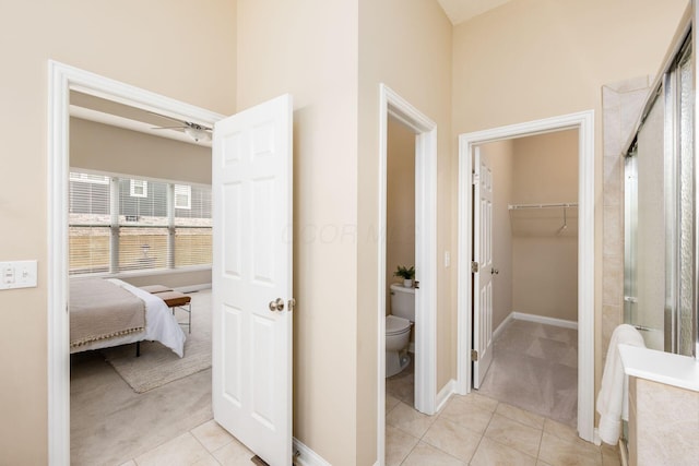 bathroom featuring toilet, a ceiling fan, a shower stall, baseboards, and tile patterned floors