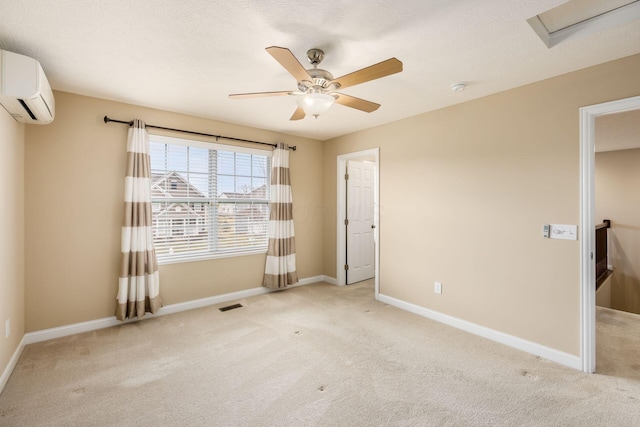 unfurnished room with light colored carpet, visible vents, an AC wall unit, ceiling fan, and baseboards