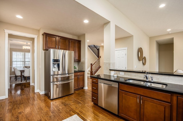 kitchen featuring dark wood-style flooring, a sink, baseboards, appliances with stainless steel finishes, and tasteful backsplash