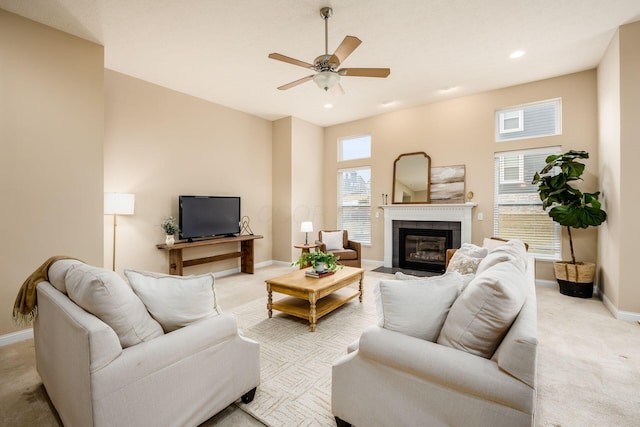 living area with light carpet, baseboards, a ceiling fan, and a tile fireplace