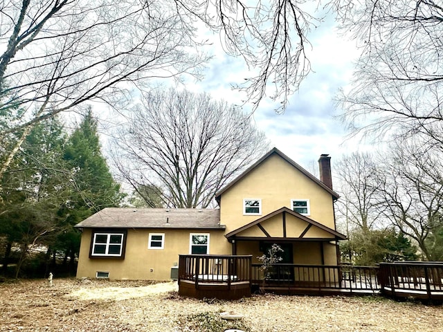 rear view of house with a chimney, a deck, and stucco siding