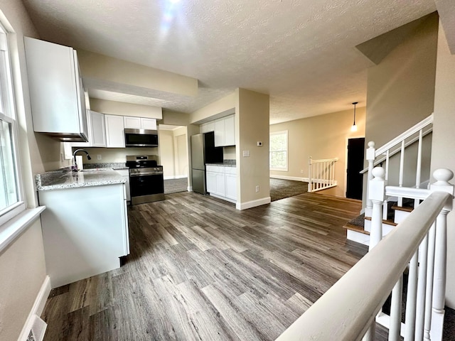 kitchen with dark wood-type flooring, a sink, white cabinetry, appliances with stainless steel finishes, and decorative light fixtures