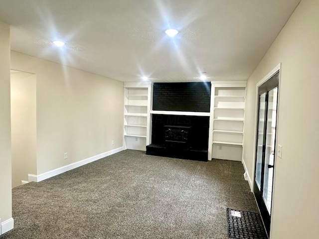 unfurnished living room featuring a fireplace with raised hearth, baseboards, built in features, and dark colored carpet