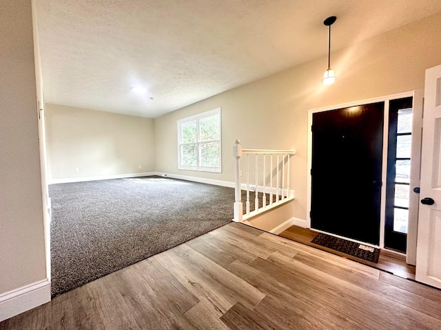 entryway featuring a textured ceiling, baseboards, and wood finished floors