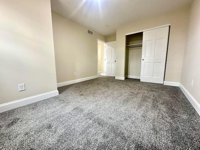 unfurnished bedroom featuring a closet, visible vents, dark carpet, and baseboards