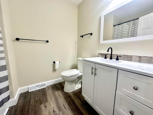 bathroom featuring toilet, wood finished floors, vanity, visible vents, and baseboards