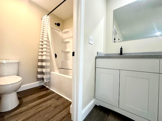 full bath with toilet, wood finished floors, vanity, baseboards, and shower / bath combination with curtain