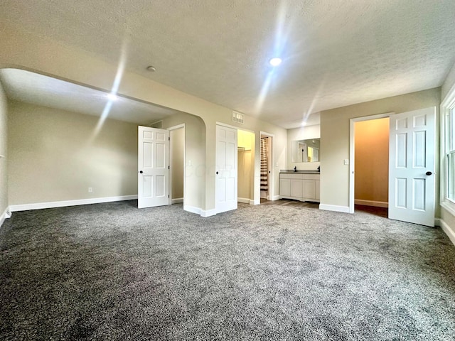 unfurnished room featuring stairway, baseboards, dark carpet, and a textured ceiling