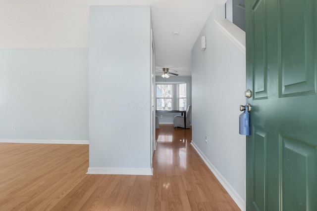 corridor with light wood-style floors and baseboards