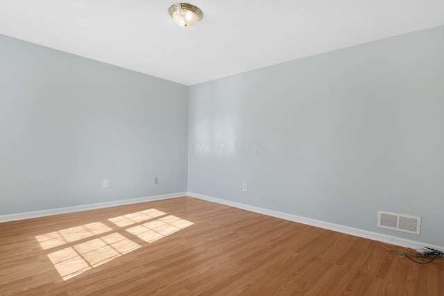 unfurnished room featuring light wood finished floors, baseboards, and visible vents