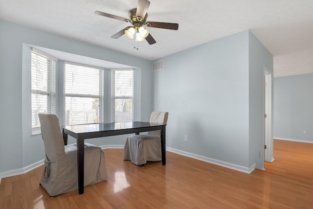 dining area with baseboards, visible vents, and light wood finished floors