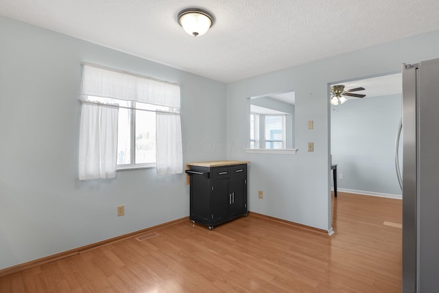 unfurnished room featuring a wealth of natural light, baseboards, visible vents, and light wood finished floors