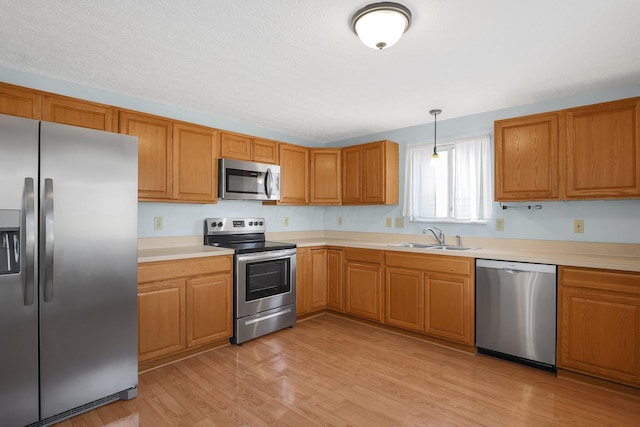 kitchen with brown cabinets, decorative light fixtures, stainless steel appliances, light countertops, and a sink