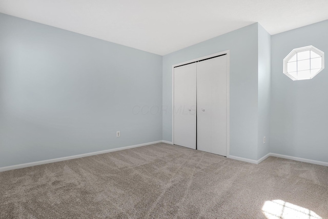 unfurnished bedroom with carpet floors, baseboards, and a closet