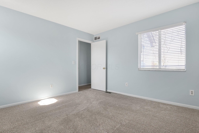 carpeted spare room with visible vents and baseboards