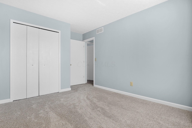 unfurnished bedroom with baseboards, visible vents, carpet, a textured ceiling, and a closet