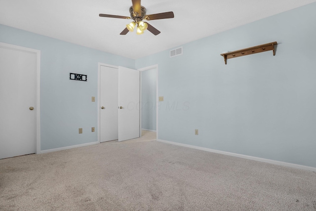 unfurnished bedroom featuring light colored carpet, visible vents, ceiling fan, and baseboards