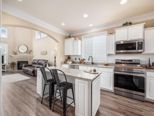 kitchen with appliances with stainless steel finishes, a center island, open floor plan, and white cabinets