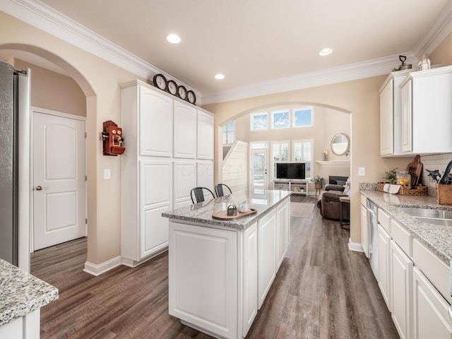 kitchen featuring a center island, dark wood-style flooring, open floor plan, white cabinets, and light stone countertops