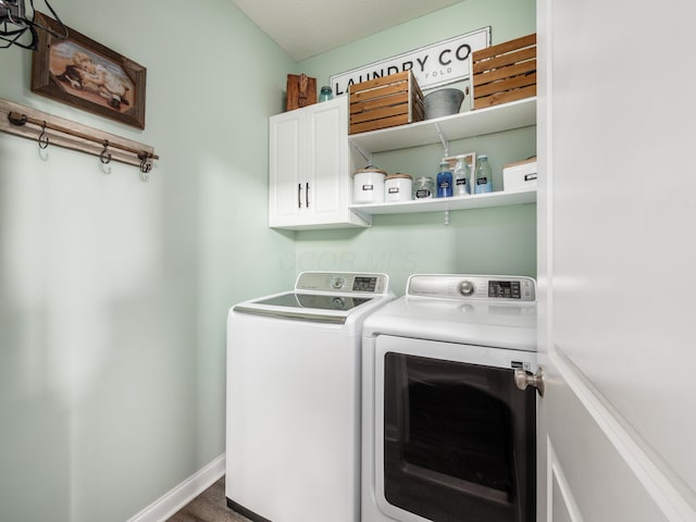 clothes washing area with washer and clothes dryer, cabinet space, and baseboards