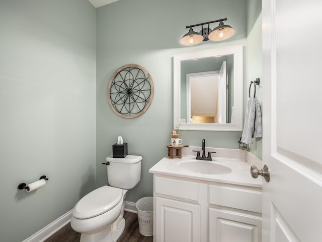 half bathroom featuring toilet, wood finished floors, vanity, and baseboards