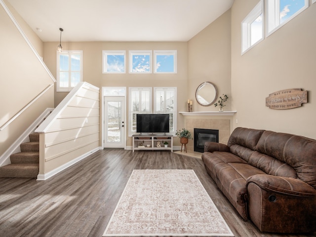 living room with a towering ceiling, stairs, a wealth of natural light, and wood finished floors