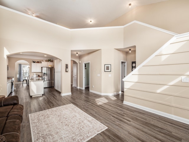 living area with arched walkways, dark wood-style flooring, and baseboards