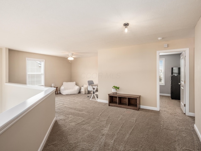 interior space with baseboards, ceiling fan, and light colored carpet