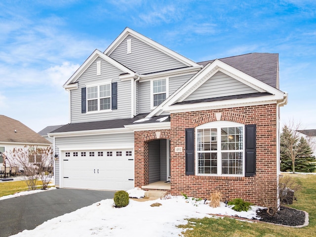 traditional-style house with an attached garage, aphalt driveway, and brick siding