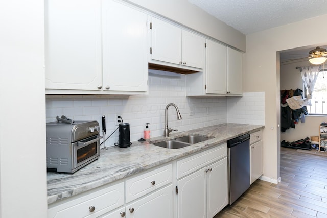kitchen with a sink, white cabinetry, decorative backsplash, a toaster, and dishwashing machine