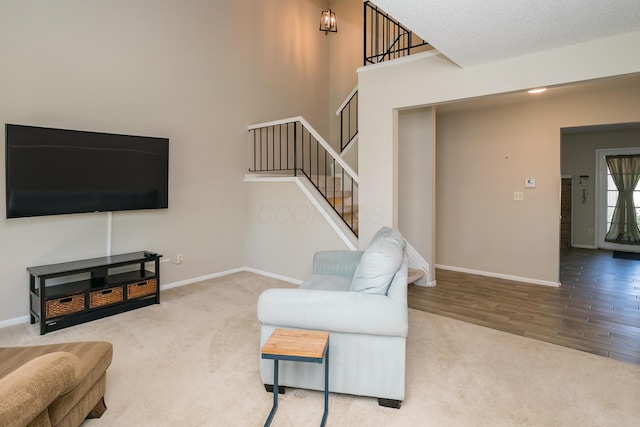 carpeted living area with stairs, baseboards, and wood finished floors