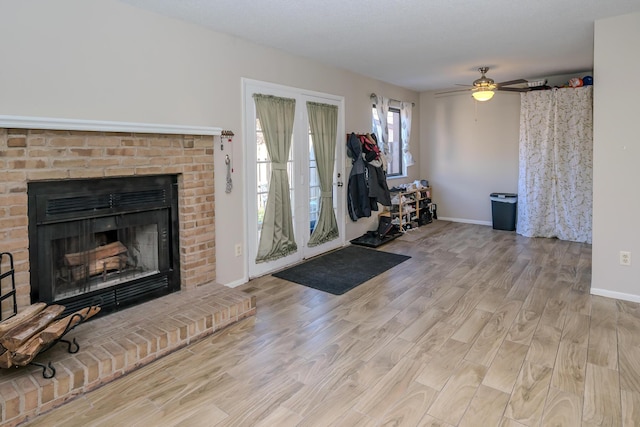 entryway featuring baseboards, ceiling fan, wood finished floors, and a fireplace