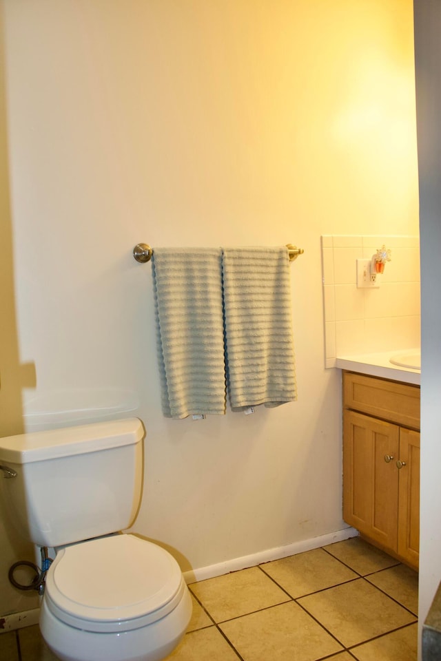 bathroom with tile patterned flooring, baseboards, vanity, and toilet