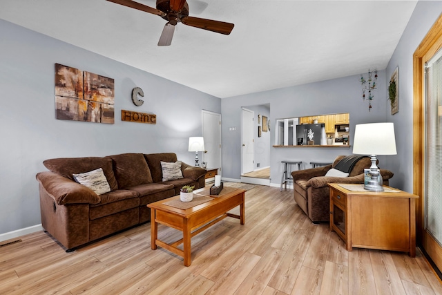 living area with a ceiling fan, baseboards, visible vents, and light wood finished floors