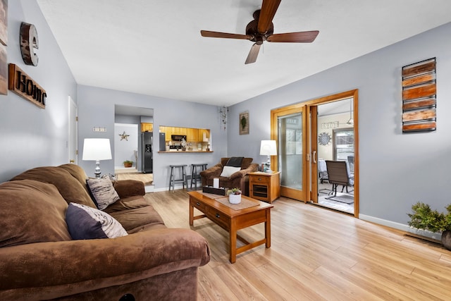 living area featuring baseboards, a ceiling fan, and light wood-style floors