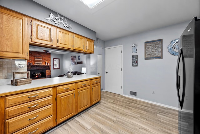 kitchen with visible vents, light countertops, light wood-type flooring, freestanding refrigerator, and tasteful backsplash