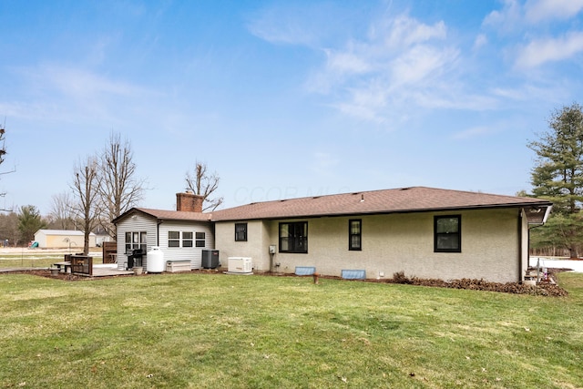 back of property with cooling unit, a yard, stucco siding, a chimney, and a patio area