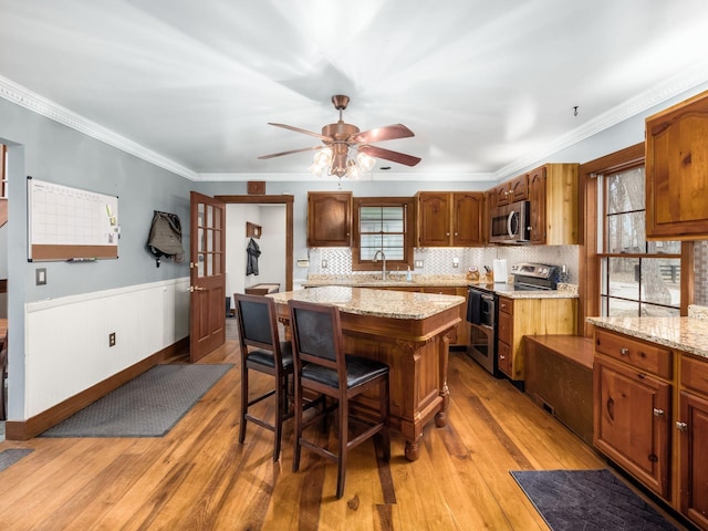 767 London Groveport Rd, Lockbourne, OH 43137 - kitchen with a breakfast bar area, light wood-style flooring, a kitchen island, appliances with stainless steel finishes, and wainscoting